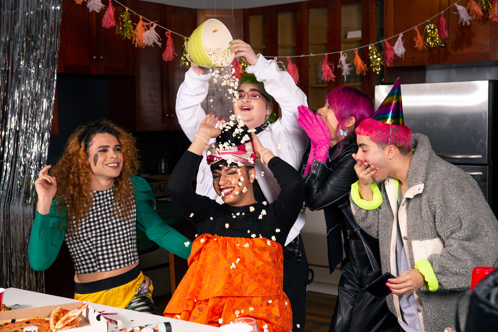 A group of friends of varying genders playing with popcorn at a party.